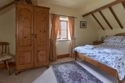 a bedroom with a bed and a wooden cabinet at Granary Cottage a Shropshire haven in Church Stretton