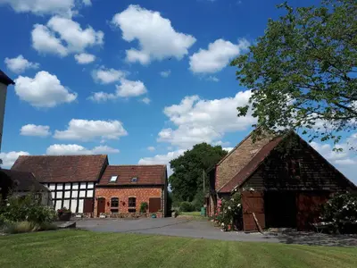 a group of three barns and a blue sky with clouds at Granary Cottage a Shropshire haven in Church Stretton