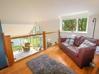 a living room with a leather couch and a balcony at Bryn Golau in Llangollen