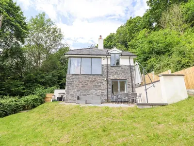 a small stone house on a hill with grass at Bryn Golau in Llangollen