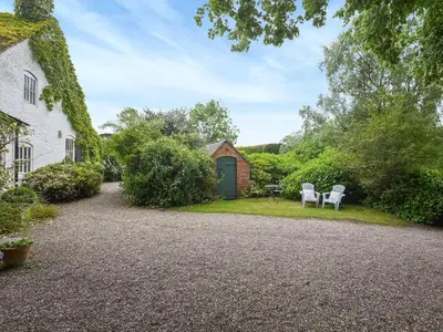a garden with two chairs and a house at Home Farm Barn in Pontesbury