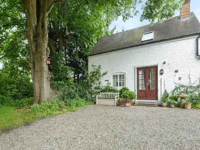a white house with a bench and a tree at Home Farm Barn in Pontesbury