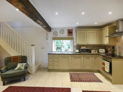 a kitchen with green cabinets and a chair and a sink at Home Farm Barn in Pontesbury