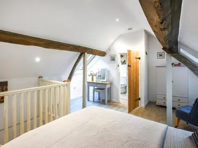 an attic bedroom with a bed and a desk at Home Farm Barn in Pontesbury