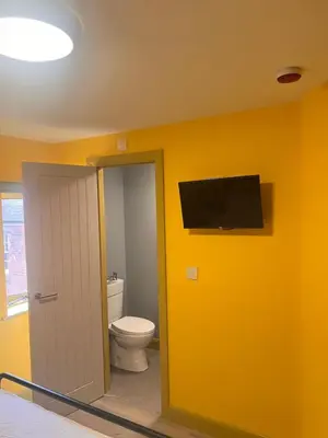 a bathroom with a toilet and a television on the wall at Tumbledown Hotel in Shrewsbury