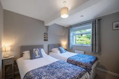 two beds in a small bedroom with a window at Modern Sea View Apartment in Aberdyfi