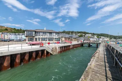 a bridge over a body of water next to a pier at Modern Sea View Apartment in Aberdyfi