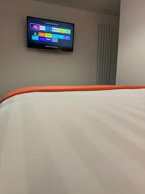a flat screen tv on a wall next to a bed at The Bear Apartments in Llandovery