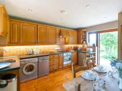 a kitchen with wooden cabinets and stainless steel appliances at The Old Chapel Charming countryside retreat - Pass the Keys in Ludlow