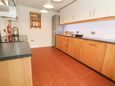 a kitchen with wooden cabinets and a red tile floor at Plum Hill in Oswestry