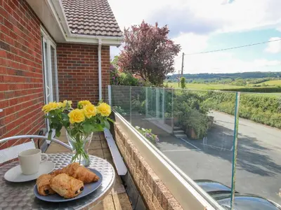 a table with a vase of flowers and bread on a balcony at Plum Hill in Oswestry