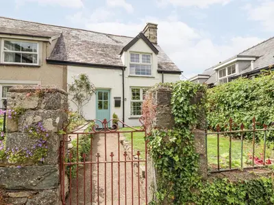 a gate in front of a house with ivy at Ivy Cottage in Harlech