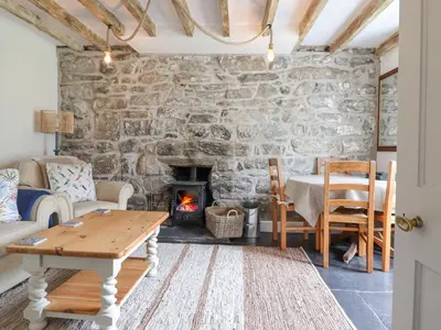a living room with a stone wall and a fireplace at Ivy Cottage in Harlech