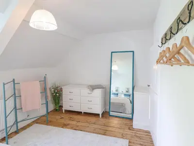 a white bedroom with a mirror and a dresser at Ivy Cottage in Harlech
