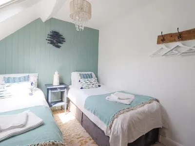 a bedroom with two beds and a chandelier at Ivy Cottage in Harlech