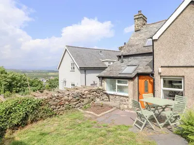 a house with a table and chairs in front of it at Ivy Cottage in Harlech