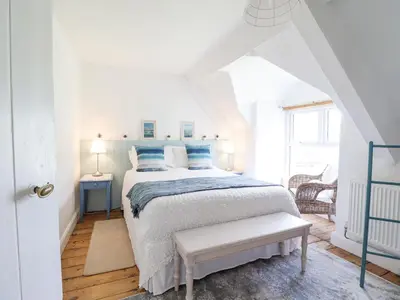 a white bedroom with a bed with blue pillows at Ivy Cottage in Harlech