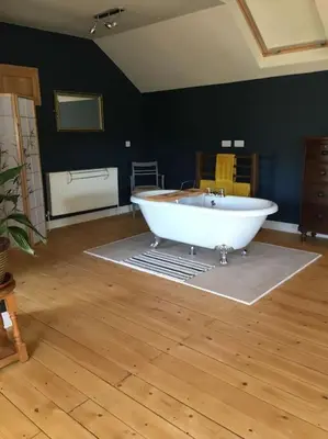 a large white tub in a room with a wooden floor at A Tranquil Retreat for Two in Pont-Robert