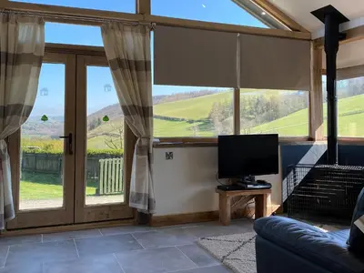 a living room with a large window and a television at Red Kite Cottage in Llangunllo