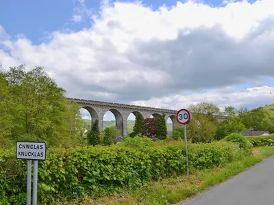 a train bridge over a road with a sign at Oak View Cottage in Llangunllo