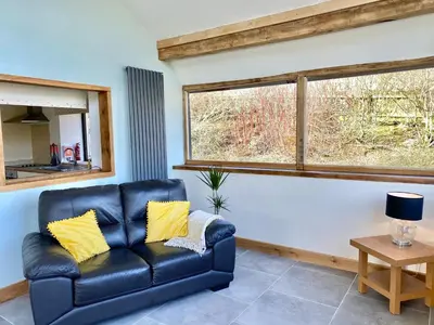 a blue leather couch in a living room with a window at Oak View Cottage in Llangunllo