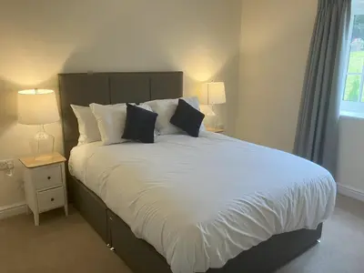 a bedroom with a large bed with white sheets and pillows at Tedsmore Cottages in Oswestry