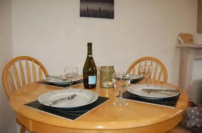 a wooden table with plates and a bottle of wine at No 6 at Dolgoch Falls Cottages in Bryn-crug