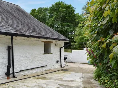 a white brick building with a window and a hedge at The Dairy - Uk47471 in Llanerch-Aeron