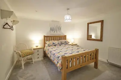 a bedroom with a bed and a mirror and a chair at Drws Y Coed in Tal-gareg