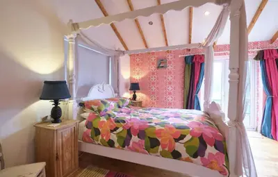a bedroom with a bed with a colorful comforter at Drws Y Coed in Tal-gareg
