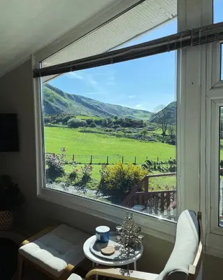 a window with a view of a green field at Cosy private Chalet in Tywyn