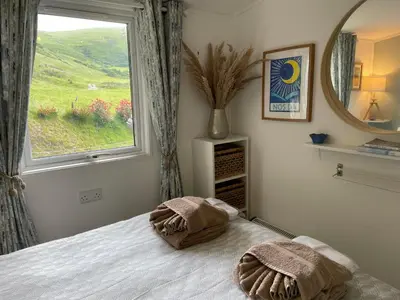 a bedroom with a bed with a large window at Cosy private Chalet in Tywyn