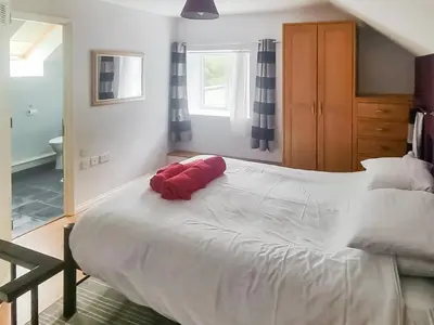 a large white bed with a red pillow on it at The Granary - Or3 in Henfynyw Upper