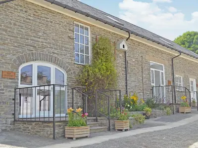 a brick building with a gate and some flowers at The Granary - Or3 in Henfynyw Upper