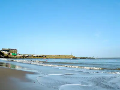 a beach with the ocean and a pier in the background at The Cow Shed - Or5 in Henfynyw Upper