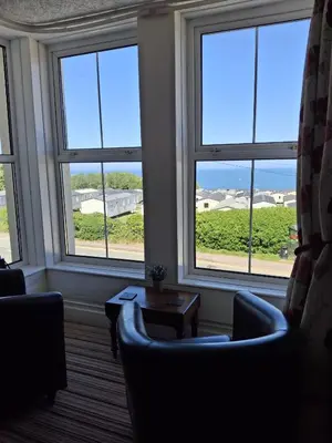 a room with two chairs and a table and windows at The Cambrian in New Quay