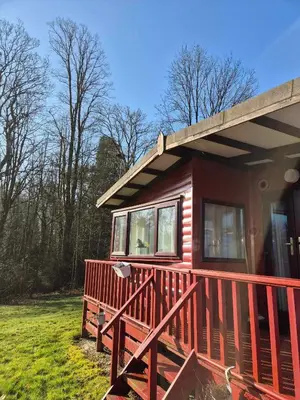a red house with a large wooden deck at Number 8 Lodge Caer Beris in Maesmynis