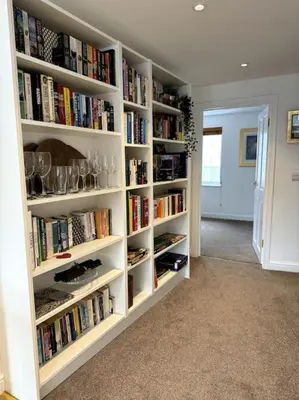 a library with white shelves filled with books at Penny Black Apartment, Kington in Kington