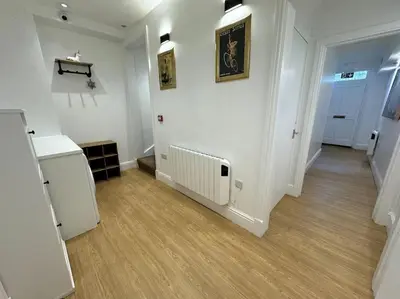 a room with a hallway with white walls and wooden floors at Penny Red apartment in Kington in Kington