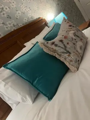 a bed with green and white pillows on it at The Bull Hotel in Ludlow