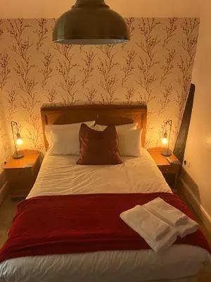 a bedroom with a bed with a red blanket and two lamps at The Bull Hotel in Ludlow