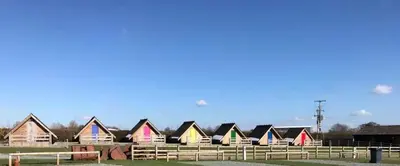 a row of colorful houses in a field at Weston glamping pod in Oswestry