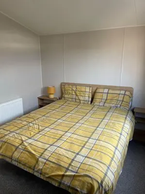 a bedroom with a bed with a yellow plaid blanket at Weston pools lodge in Oswestry