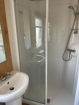 a white bathroom with a shower and a sink at Weston pools lodge in Oswestry