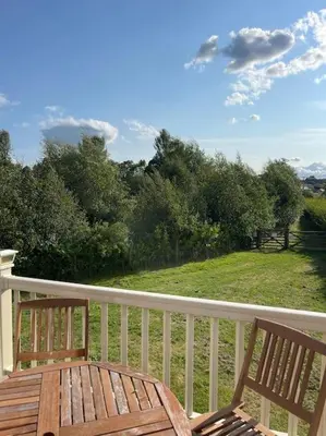 a wooden table and two chairs on a porch at Weston pools lodge in Oswestry