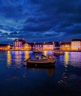 a boat in the water in front of buildings at night at Sea Breeze Lodge in Aberaeron