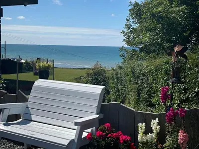 a white bench sitting next to a fence and flowers at Sea Breeze Lodge in Aberaeron