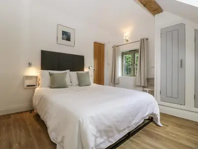 a white bedroom with a large bed with white sheets at The Coach House in Ludlow