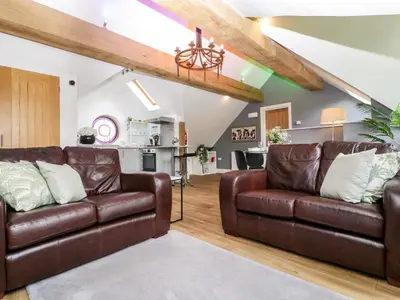 a living room with two brown leather couches and a kitchen at The Coach House in Ludlow