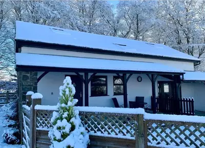 a cottage covered in snow with a fence at Frondeg Bach in Tregaron